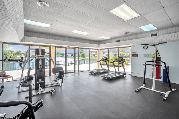 Indoor gym area with exercise equipment and large windows.