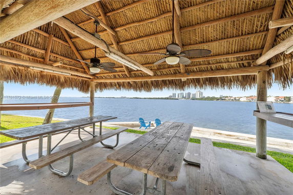 Thatched roof structure with picnic tables overlooking a waterfront view.