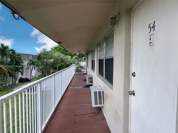 Exterior walkway view of a building with unit doors and railing.