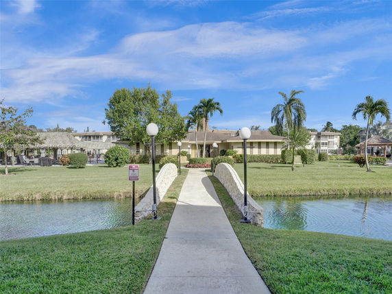 Front view of a building with a pathway and a small bridge over water leading to it.
