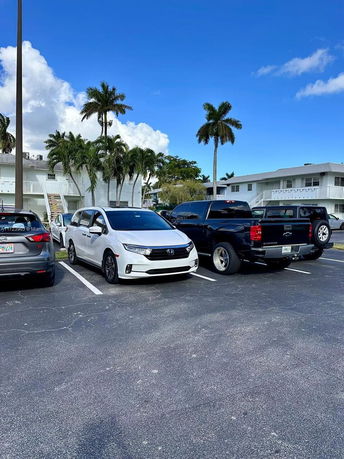 Outdoor parking area with several parked cars near a building.
