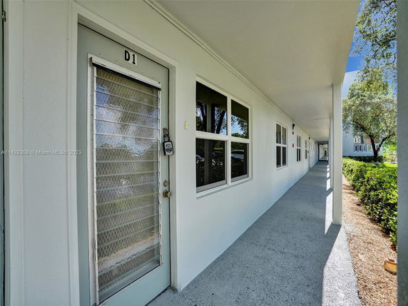 Exterior walkway of a building with multiple windows and entrance doors.