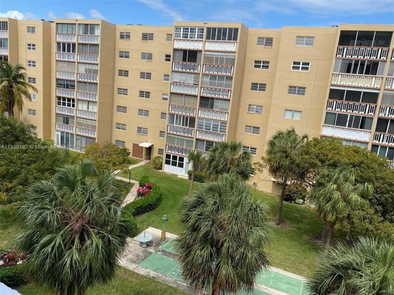 View of a multi-story residential building with balconies and surrounding greenery.