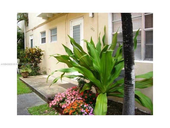 Front view of a building with a door and windows, surrounded by plants.