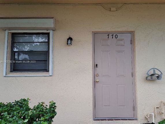 Front view of a building with a beige door labeled 110 and a window on the left.
