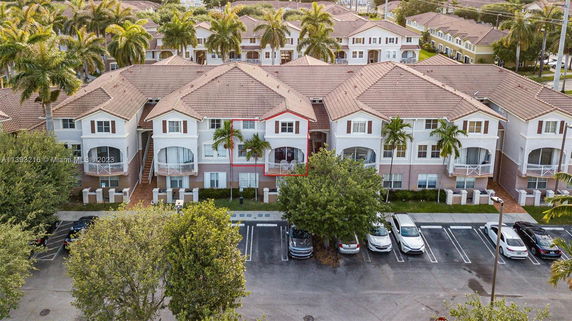 Aerial view of a residential complex with multiple two-story buildings featuring balconies and a parking area in front.
