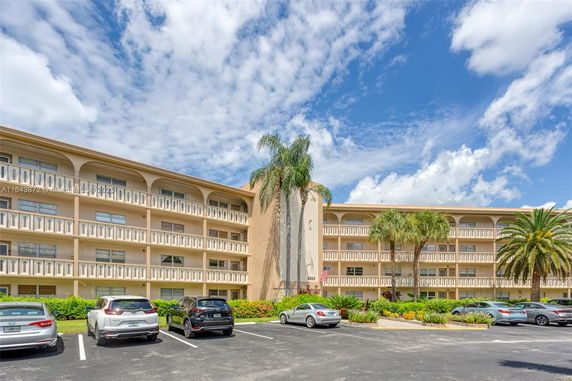 Front view of a multi-story residential building with balconies and parking area.