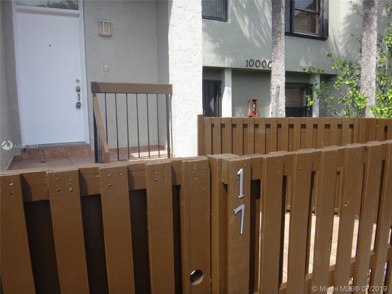 Front view of a building entrance with a wooden fence and porch.