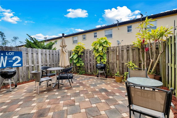 Outdoor patio area with tables, chairs, and a wooden fence.
