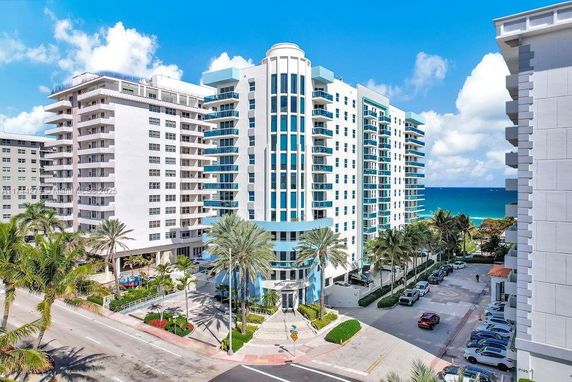 Front view of a multi-story residential building with balconies and large glass windows.
