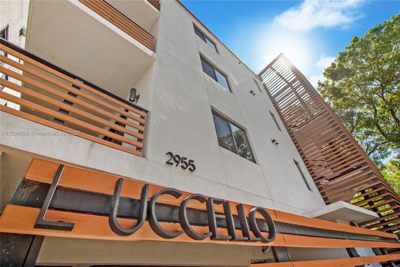 Front view of a modern multi-story building with wooden accents and signage.