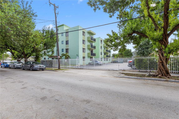 Front view of a multi-story apartment building with a gated parking area.