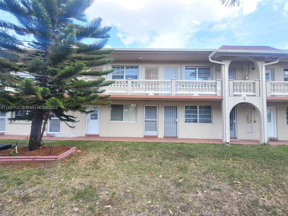 Front view of a two-story residential building with balconies and a garden.