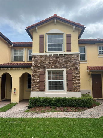 Front view of a two-story townhouse with stone accents and a red-tiled roof.