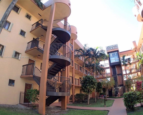 View of a multi-story apartment building with spiral staircase and gardens.