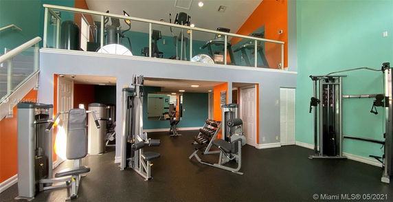 Gym area with various exercise equipment and a mezzanine with cardio machines.