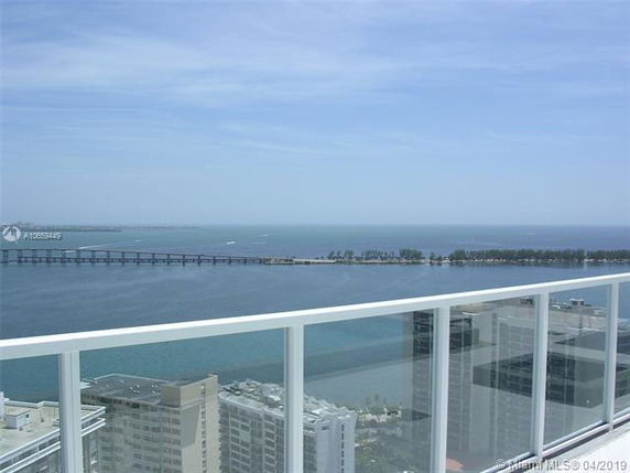 A panoramic view from a high-rise building showing the ocean and a distant bridge.