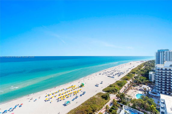 Wide angle view of a beach and ocean with nearby buildings in the distance.