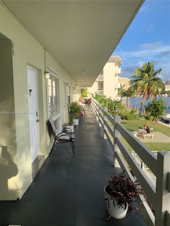 View from a balcony walkway of an apartment building overlooking a grassy area and water body.
