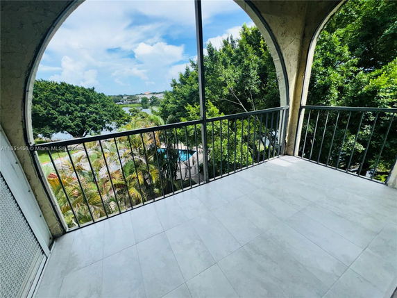 Balcony with a view of trees and distant water body.