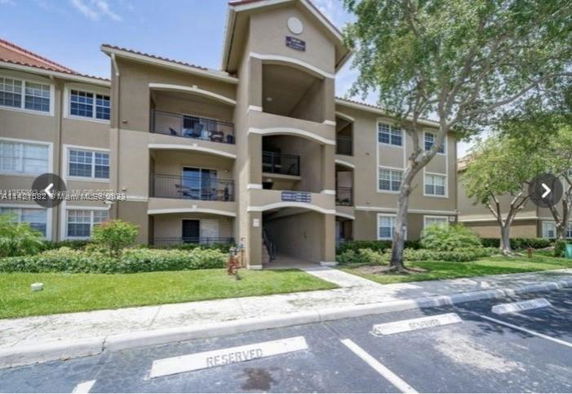 Front view of a multi-story residential building with balconies and a driveway.