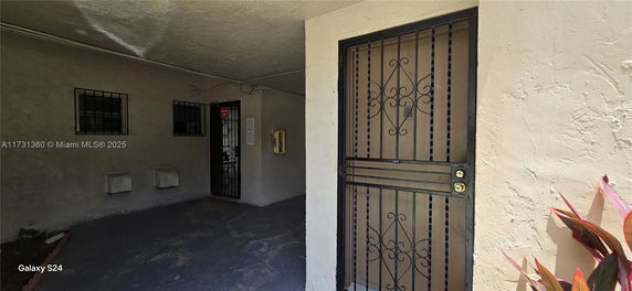 View of a building entrance with a metal security door and barred windows.
