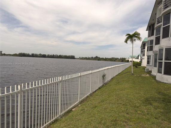 Side view of buildings adjacent to a water body with a white fence along the edge.