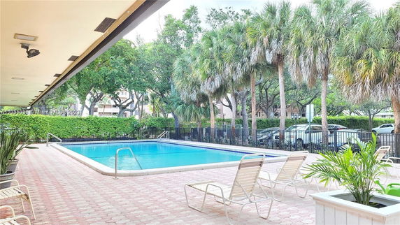 Outdoor swimming pool area with lounge chairs and surrounding greenery.