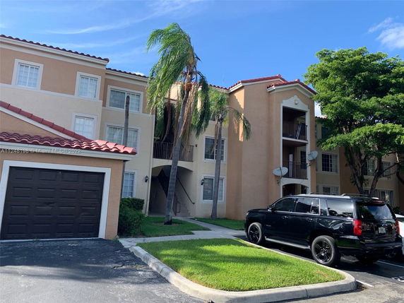 Front view of a multi-story residential building with a garage and parking area.