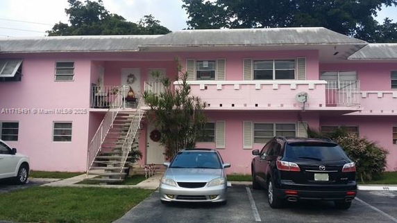 Front view of a two-story pink apartment building with exterior stairway.