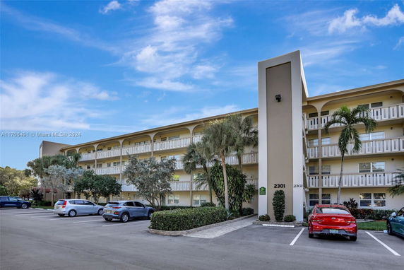 Front view of a multi-story apartment building with parking spaces in front.