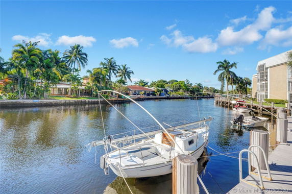 View of a waterfront area with docks, boats, and palm trees along the shore.