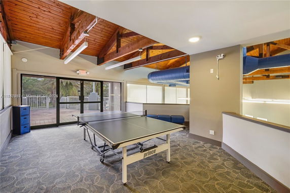 Indoor recreational area with a ping pong table and wooden ceiling beams.