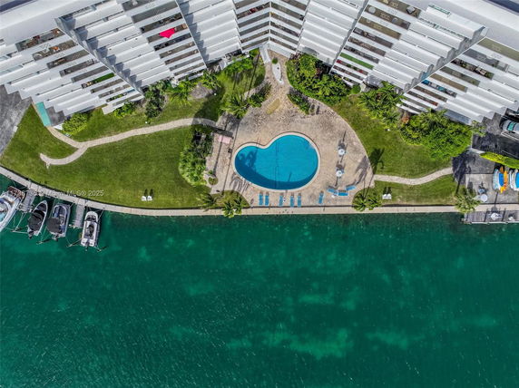 Aerial view of a swimming pool adjacent to a waterfront building.