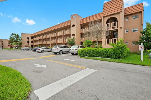 Front view of a multi-story building with balconies and parking area.