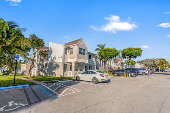 View of a multi-story residential building with a parking area in front.