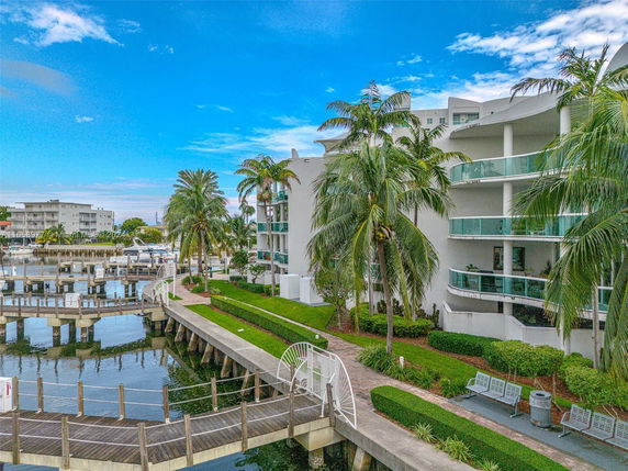 View of waterfront apartments with balconies and palm trees