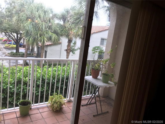 View from a balcony showing nearby buildings and palm trees.