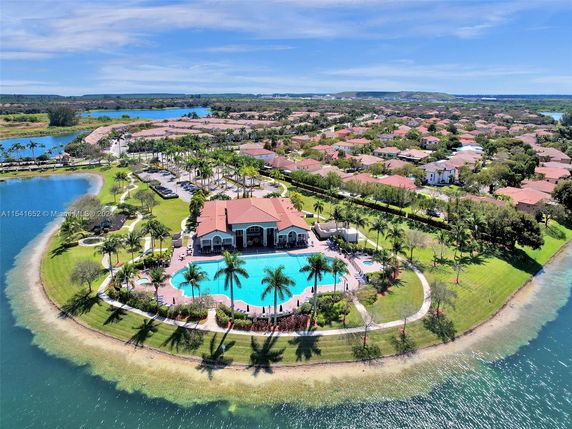 Aerial view of a neighborhood with a central clubhouse and swimming pool surrounded by water.