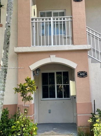 Front view of a two-story building with a small balcony and doorway labeled 102.