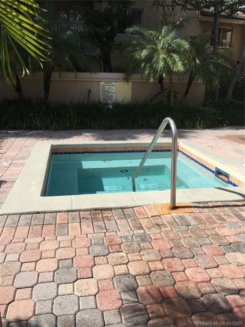 Outdoor view of a small swimming pool with surrounding paver stones.