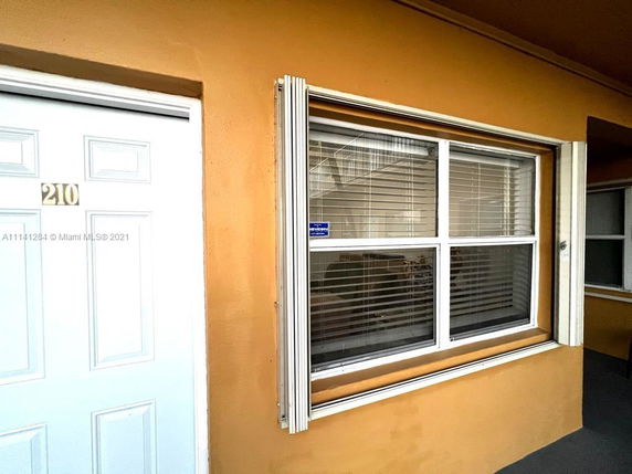 Front view of a building with a white door and a window with blinds.