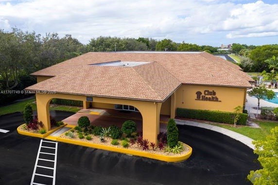 Front view of a single-story building with a tan roof and parking area.