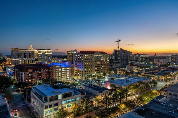 Panoramic view of a cityscape at dusk with illuminated buildings and a skyline.