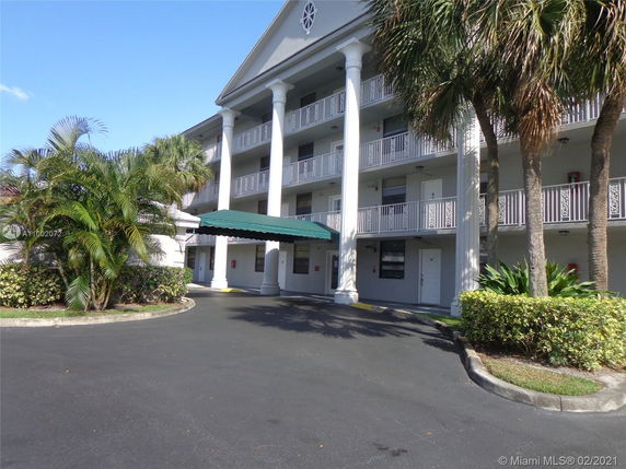 Front view of a multi-story building with columns and a green canopy.