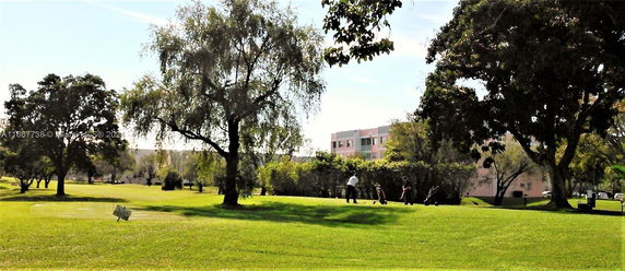 View of landscaped area with trees and a building in the background.