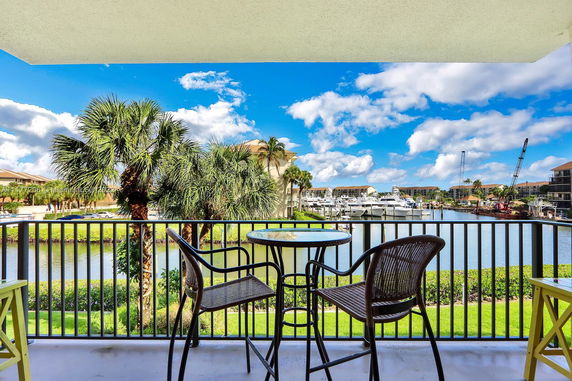 View from a balcony showing a marina with boats and palm trees.