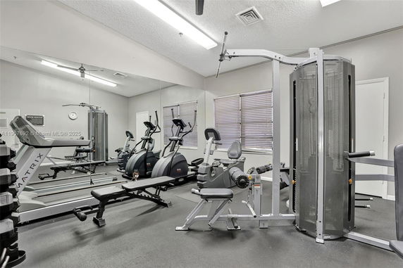 Indoor gym area with various exercise equipment, including a treadmill, elliptical machines, and weight machines.