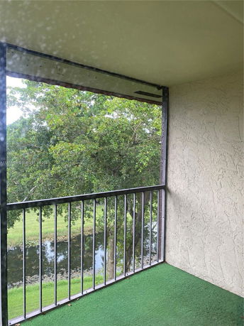 View from a balcony showing trees and a small body of water.