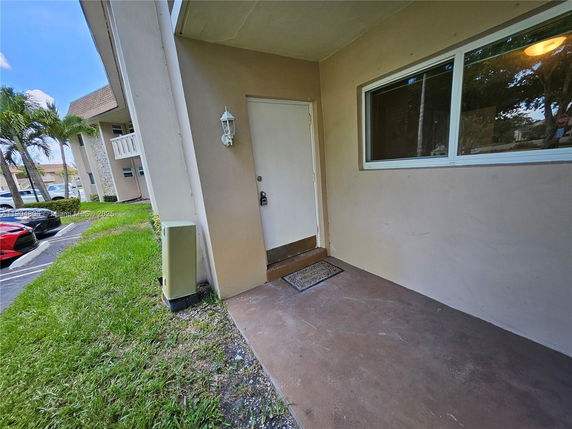Front view of a ground-floor apartment entrance with a white door and window.
